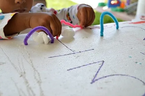 toddler playing with pipe cleaners