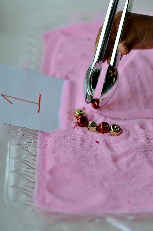using tongs and bells in fine motor peppermint tray