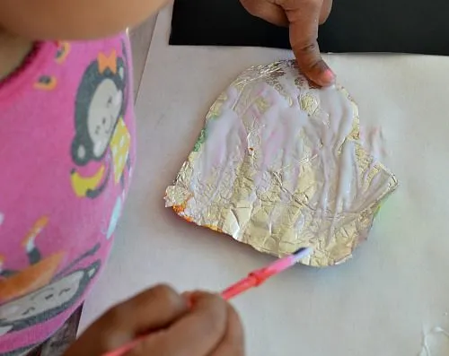 gluing foil hearts to black paper
